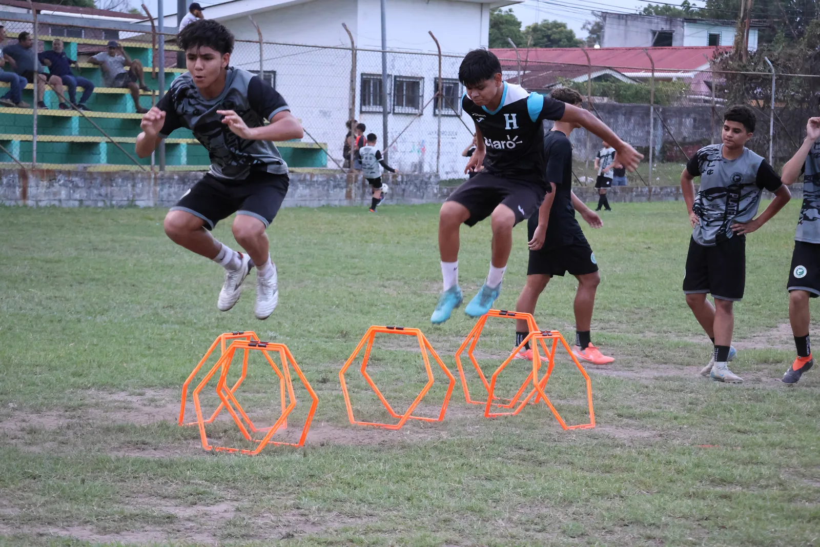 Grupo de jugadores saltando vallas en un entrenamiento